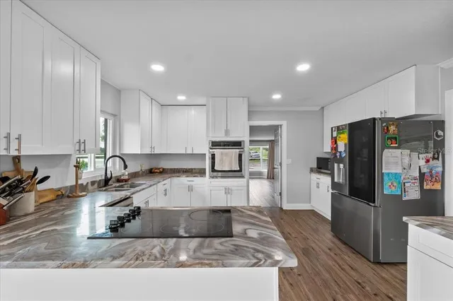 a large kitchen with granite countertop a large counter top stainless steel appliances and cabinets