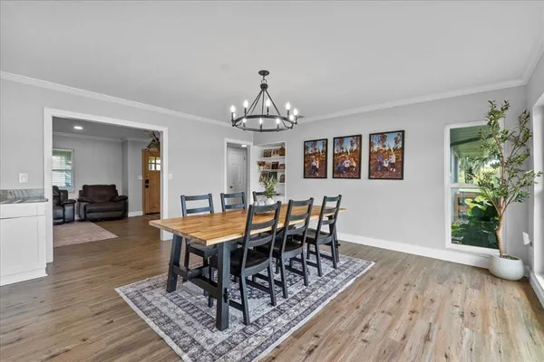 a dining room with wooden floor a chandelier a wooden table and chairs