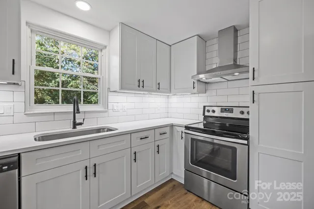 a kitchen with cabinets stainless steel appliances a sink and window