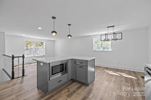 an empty room with wooden floor cabinet and windows
