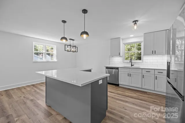 a kitchen with a sink a stove cabinets and wooden floor