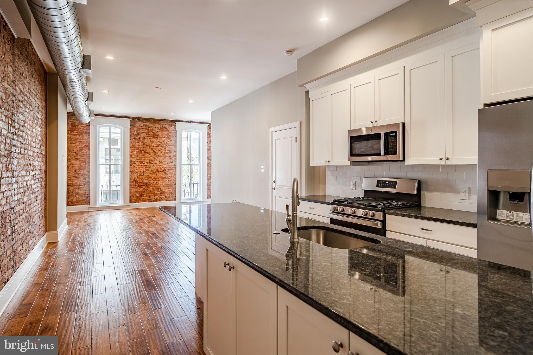 226 Bridge Street, Unit 2 Phoenixville, PA 19460 - Photo 2 of 25 a kitchen with stainless steel appliances granite countertop a stove a sink a refrigerator white cabinets and wooden floor