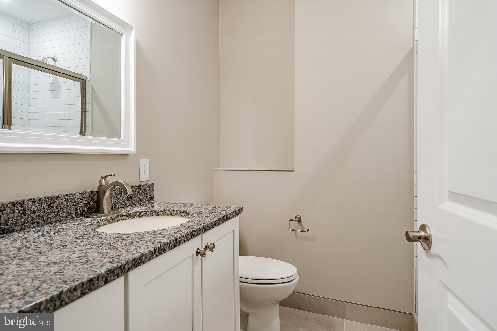 226 Bridge Street, Unit 2 Phoenixville, PA 19460 - Photo 18 of 25 a bathroom with a granite countertop sink a toilet and mirror