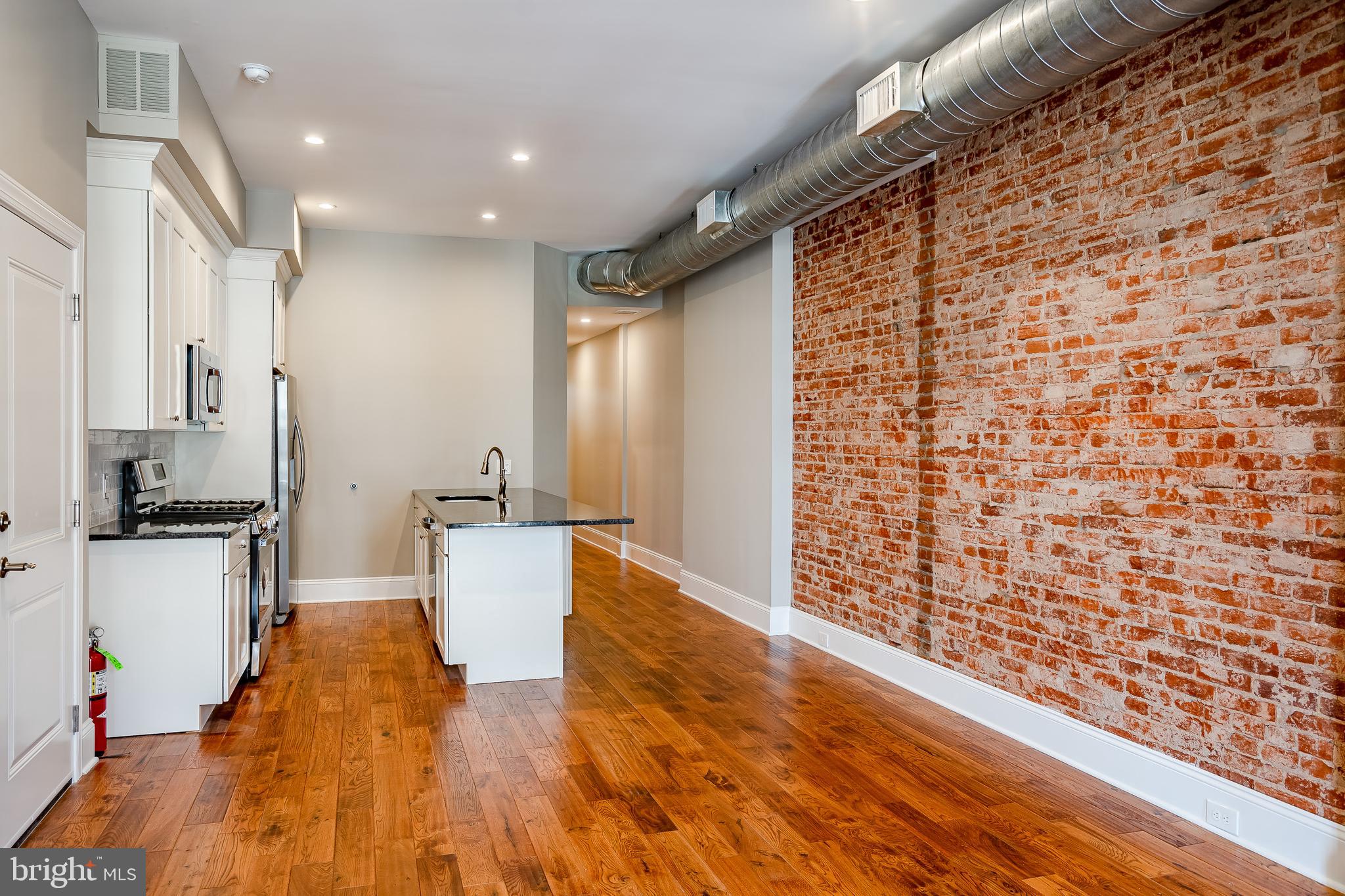 226 Bridge Street, Unit 2 Phoenixville, PA 19460 - Photo 7 of 25 a kitchen with granite countertop white cabinets and stainless steel appliances