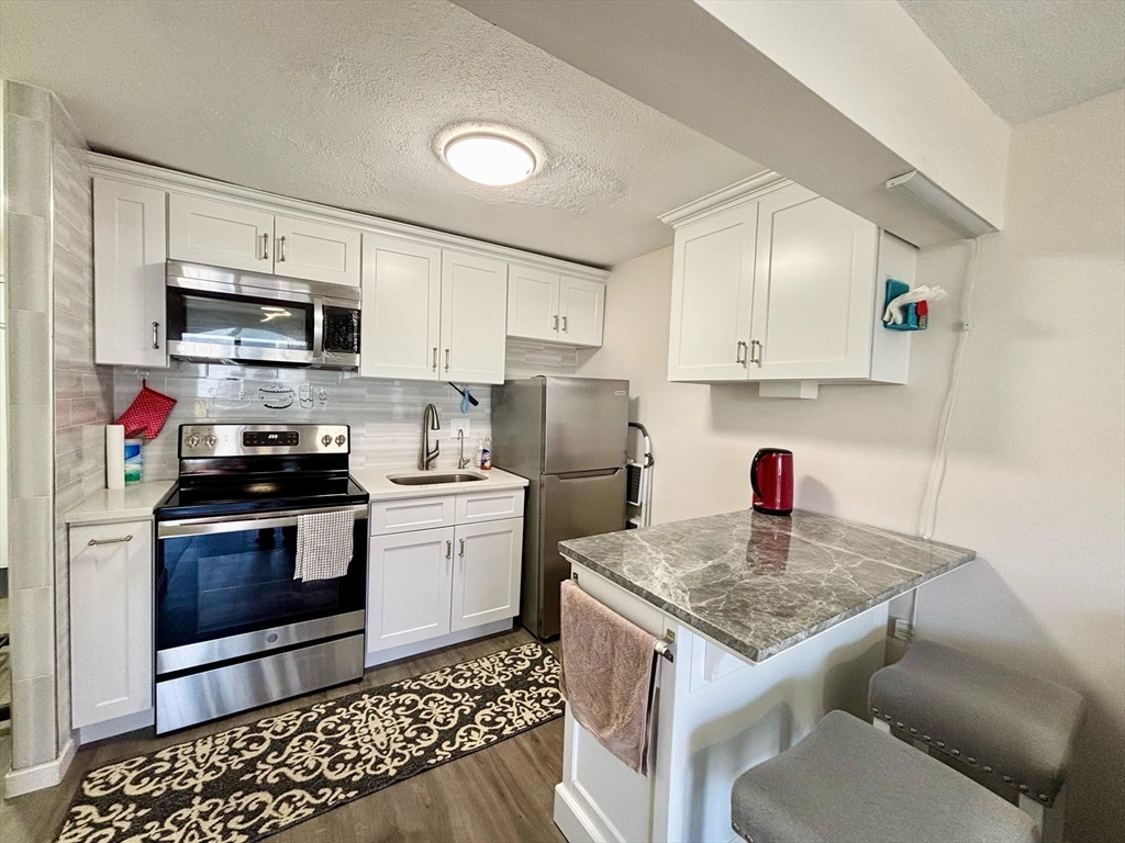 175 Ward Street, Unit 35 Revere, MA 02151 - Photo 3 of 19 a kitchen with stainless steel appliances granite countertop a sink dishwasher stove and refrigerator with wooden cabinets
