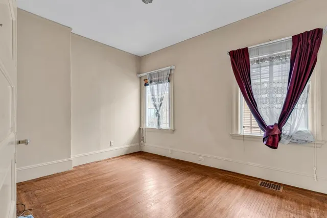 a view of a hallway with wooden floor and a bathroom