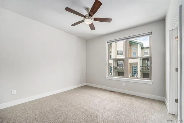 an empty room with ceiling fan and windows