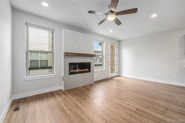 an empty room with wooden floor ceiling fan and windows
