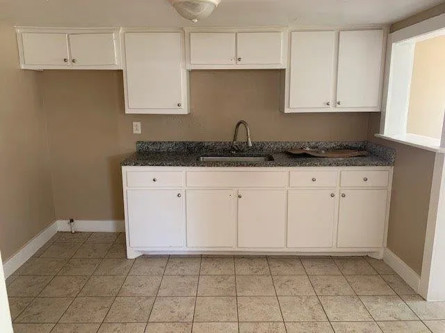 a kitchen with granite countertop white cabinets and sink