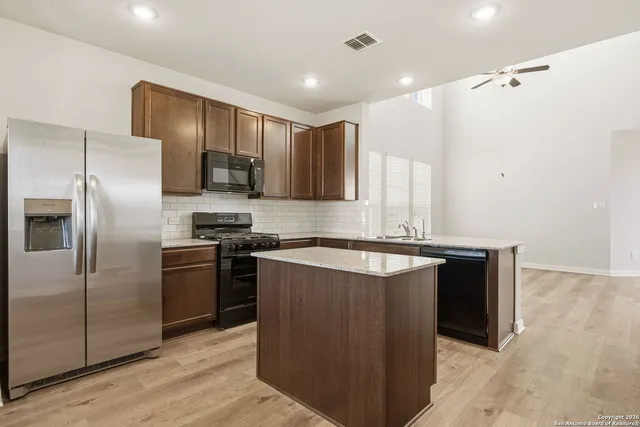 a kitchen with stainless steel appliances granite countertop a refrigerator a sink and a stove