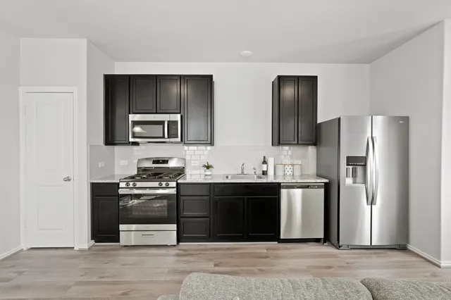 a kitchen with stainless steel appliances granite countertop a refrigerator stove and sink