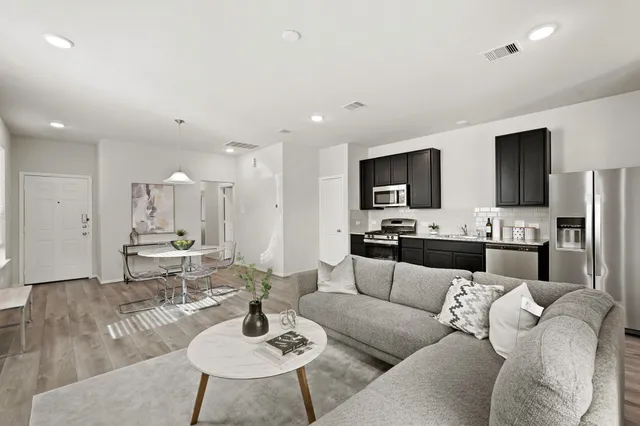a living room with stainless steel appliances kitchen island granite countertop a couch and a flat screen tv