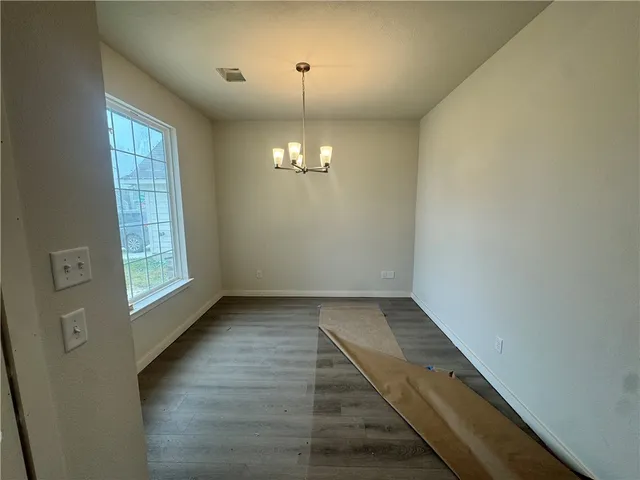 an empty room with chandelier fan and windows