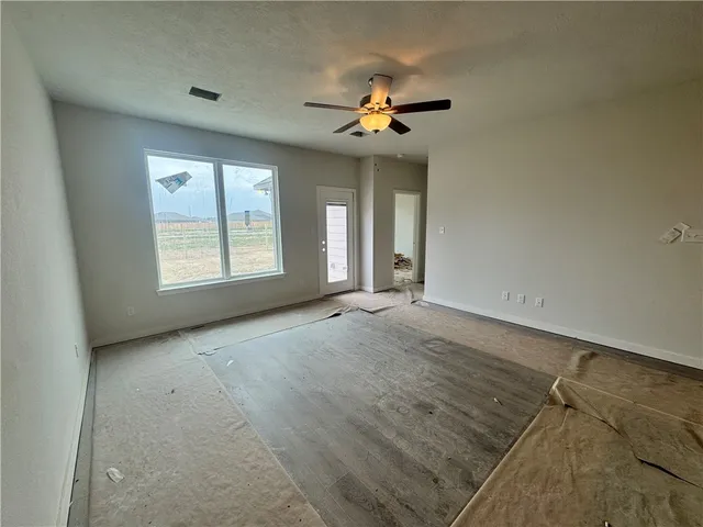 an empty room with chandelier fan and windows