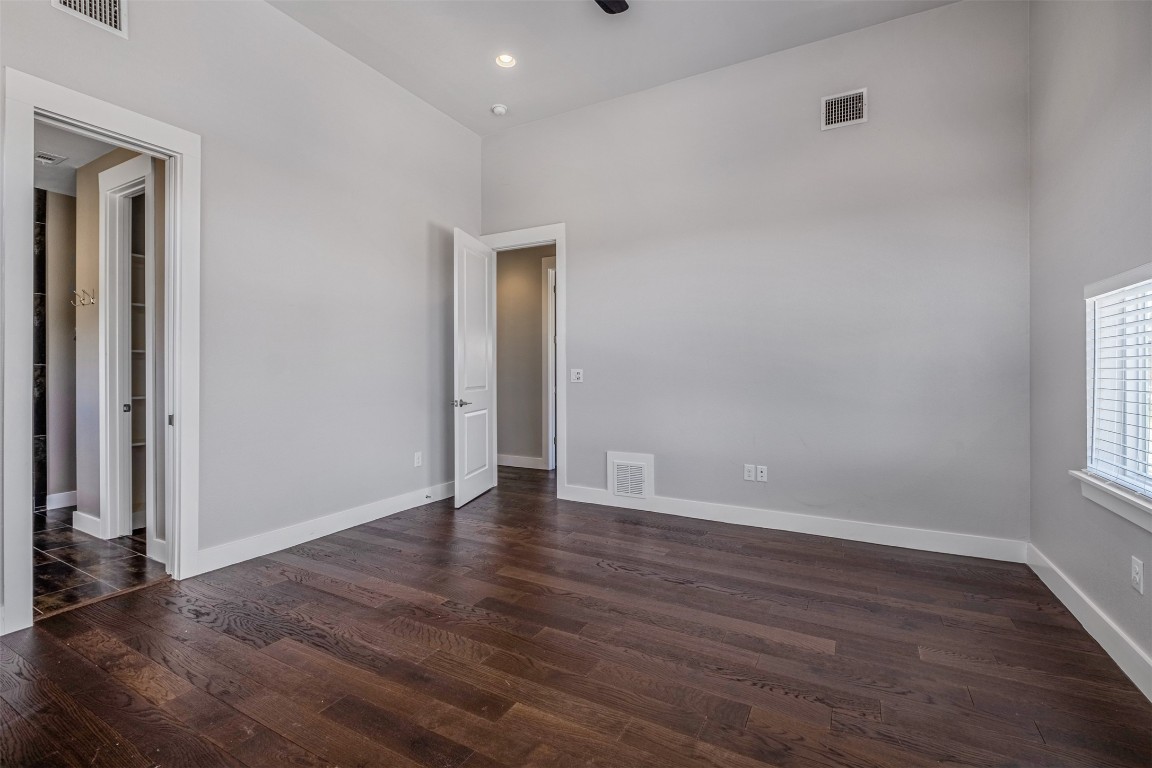 4707 Leslie Avenue, Unit A Austin, TX 78721 - Photo 19 of 24 Unfurnished bedroom featuring dark wood-type flooring, a ceiling fan, a high ceiling, and recessed lighting