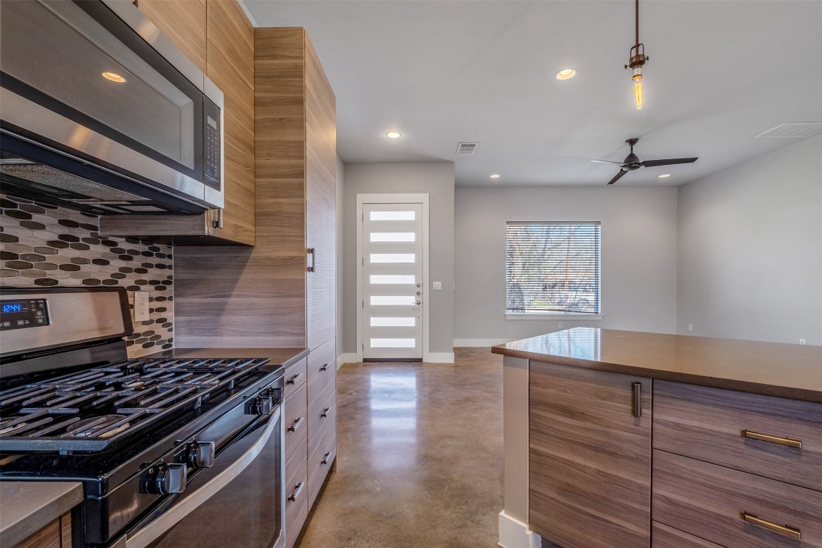4707 Leslie Avenue, Unit A Austin, TX 78721 - Photo 9 of 24 Kitchen with stainless steel appliances, concrete floors, recessed lighting, brown cabinets, and a ceiling fan