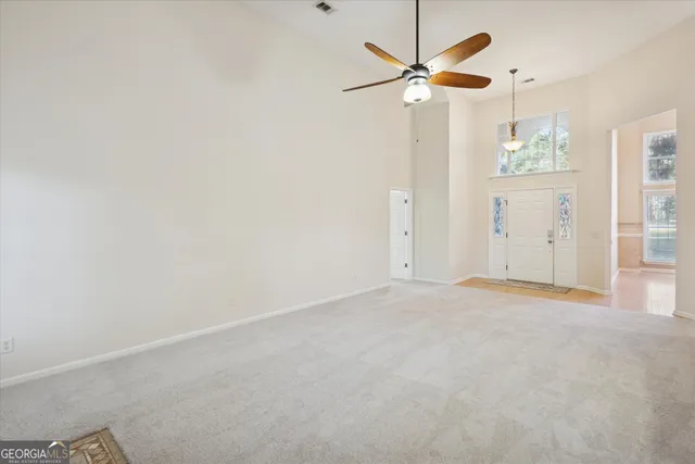 an empty room with windows and fan