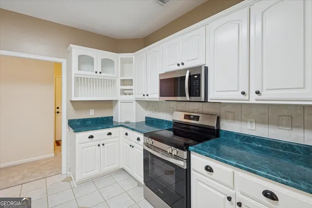 a kitchen with granite countertop white cabinets and stainless steel appliances