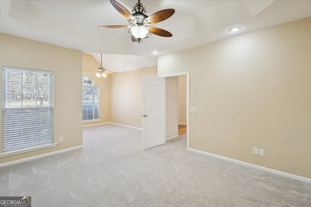 an empty room with chandelier fan and windows