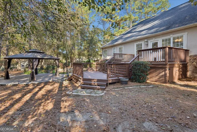 a backyard of a house with table and chairs under an umbrella
