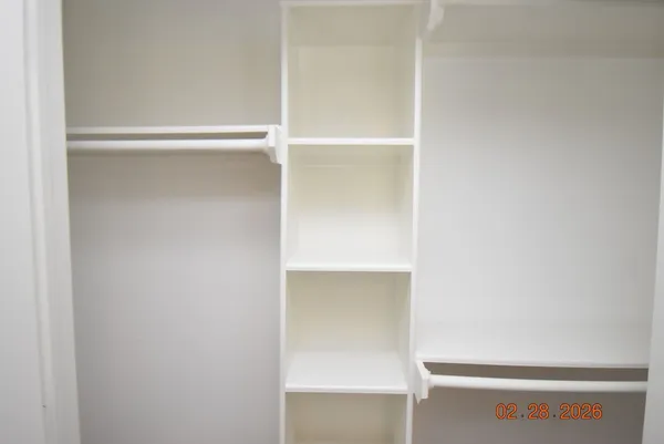 an empty room with wooden floor ceiling fan and windows