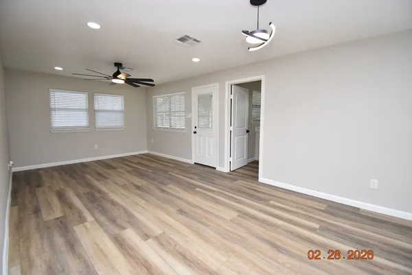 a view of empty room with wooden floor and fan