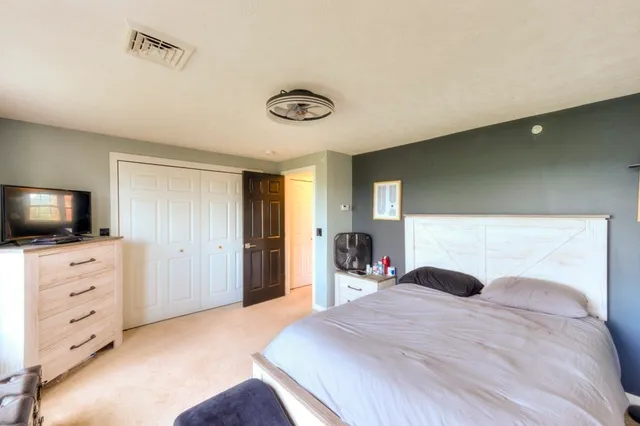 a bedroom with a bed and a flat tv screen on the dresser