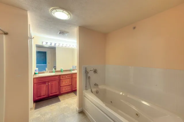 a spacious bathroom with a bathtub sink and mirror