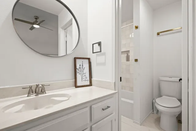 a bathroom with a granite countertop sink mirror vanity and toilet