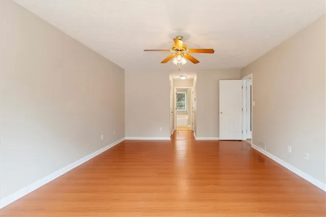 a view of an empty room with wooden floor and a window