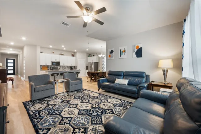 a kitchen with stainless steel appliances granite countertop a stove a refrigerator a kitchen island a dining table and chairs with wooden floor