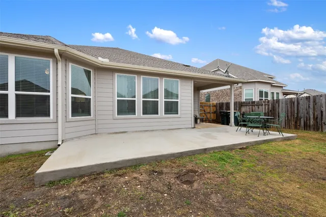 a view of a house with wooden fence next to a yard