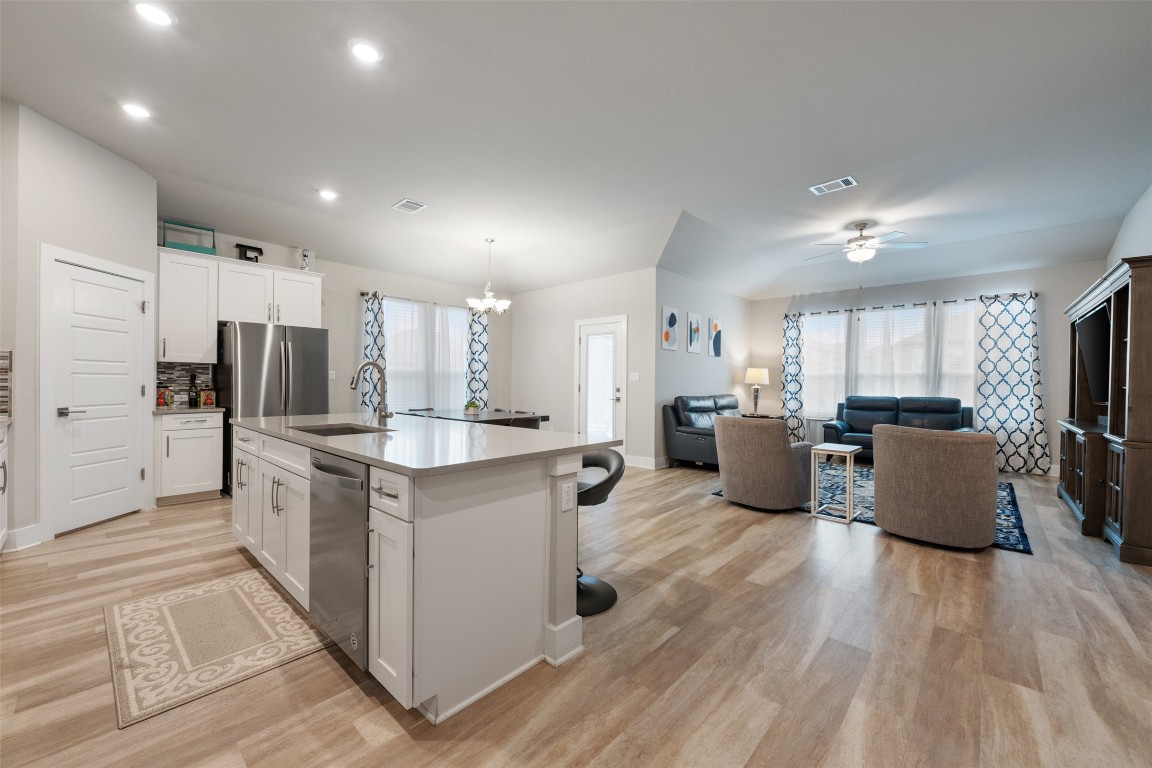 2212 Prairie Oaks Drive Georgetown, TX 78628 - Photo 10 of 39 a kitchen with stainless steel appliances kitchen island granite countertop a refrigerator a stove a sink dishwasher a dining table and chairs with wooden floor