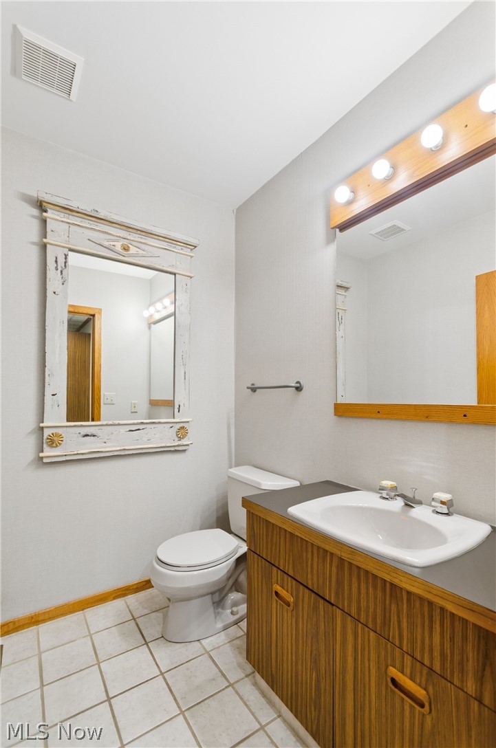 200 Hampshire Road Akron, OH 44313 - Photo 22 of 50 White tile flooring, wood-finish vanity with integrated sink, wood-finish wall mirror with decorative details, and a toilet