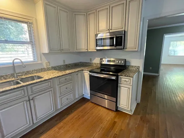 a kitchen with stainless steel appliances granite countertop a stove a sink and a microwave