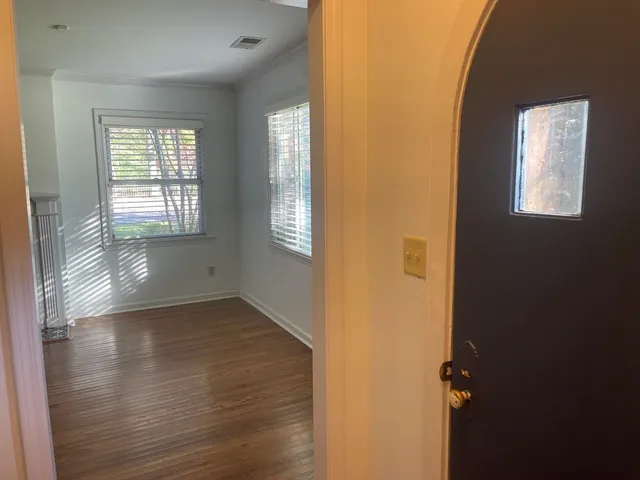 a view of an empty room with wooden floor and a window