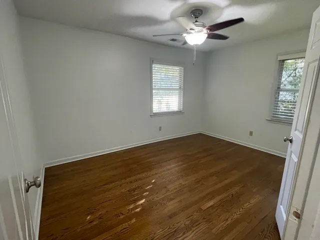 an empty room with wooden floor and fan