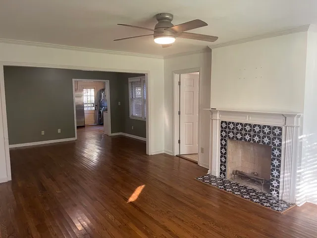 a view of a livingroom with wooden floor a ceiling fan and a fireplace