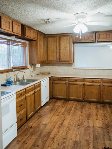 a large kitchen with granite countertop a sink cabinets and wooden floor