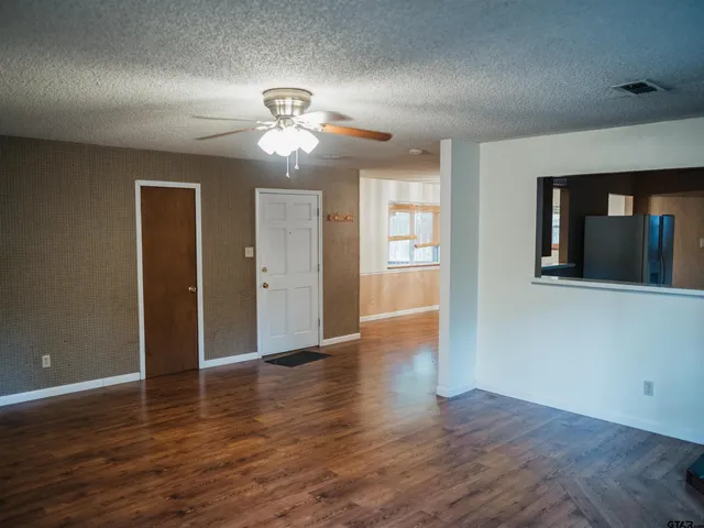 a view of an empty room with wooden floor and a window