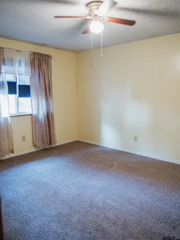 an empty room with a ceiling fan and carpet