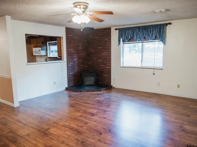 a view of an empty room with a window and wooden floor
