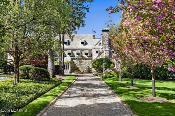 a front view of a house with a yard and large trees
