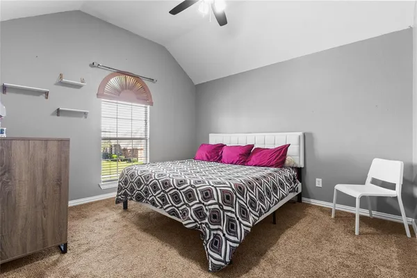 a bedroom with a bed a chandelier and a window