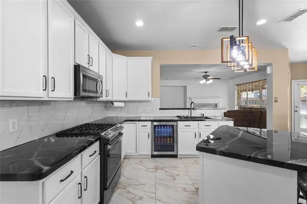 a kitchen with stainless steel appliances granite countertop a sink dishwasher stove and white cabinets with wooden floor