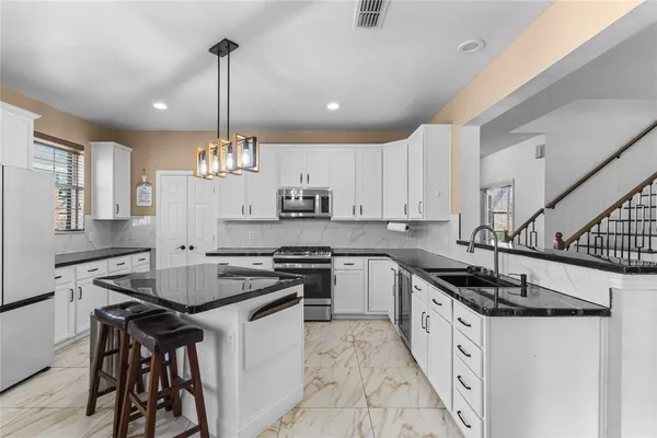 a kitchen with granite countertop a sink a counter space appliances and cabinets