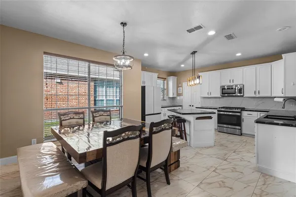 a kitchen with stainless steel appliances granite countertop a stove top oven a sink dishwasher a dining table and chairs with wooden floor