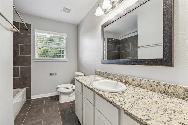a bathroom with a granite countertop sink a mirror and a toilet