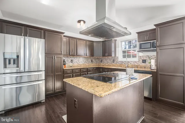 a kitchen with kitchen island a counter top space a sink appliances and cabinets