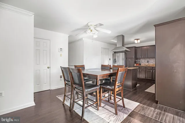 a kitchen with stainless steel appliances kitchen island granite countertop a refrigerator a stove a microwave oven a sink with island chairs and wooden floor